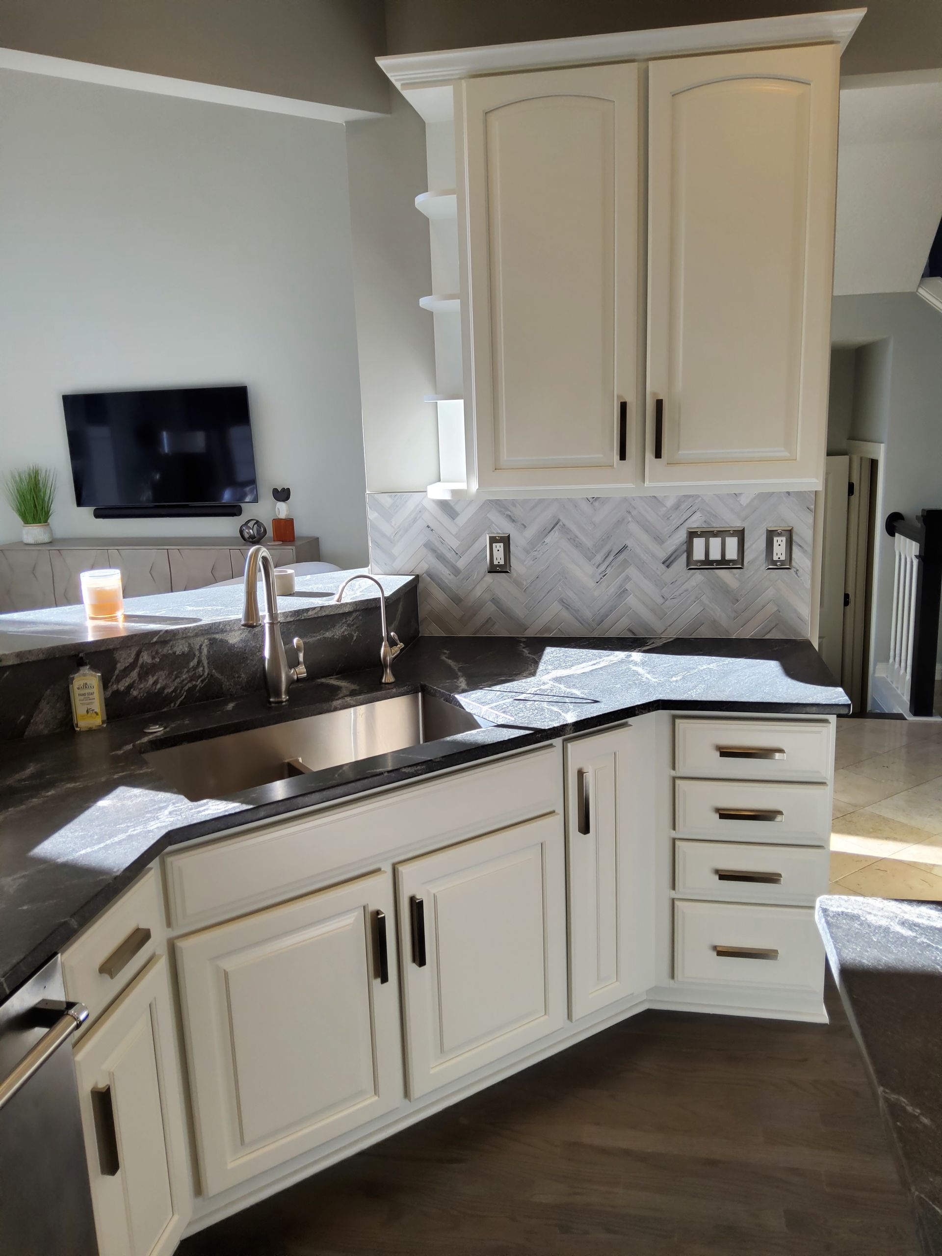 A kitchen with white cabinets and a stainless steel sink