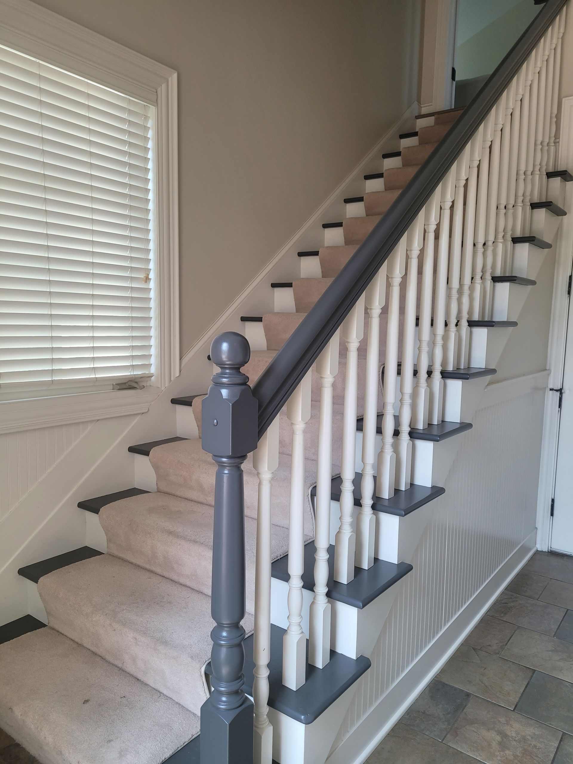 A staircase with a gray railing and a window in the background.