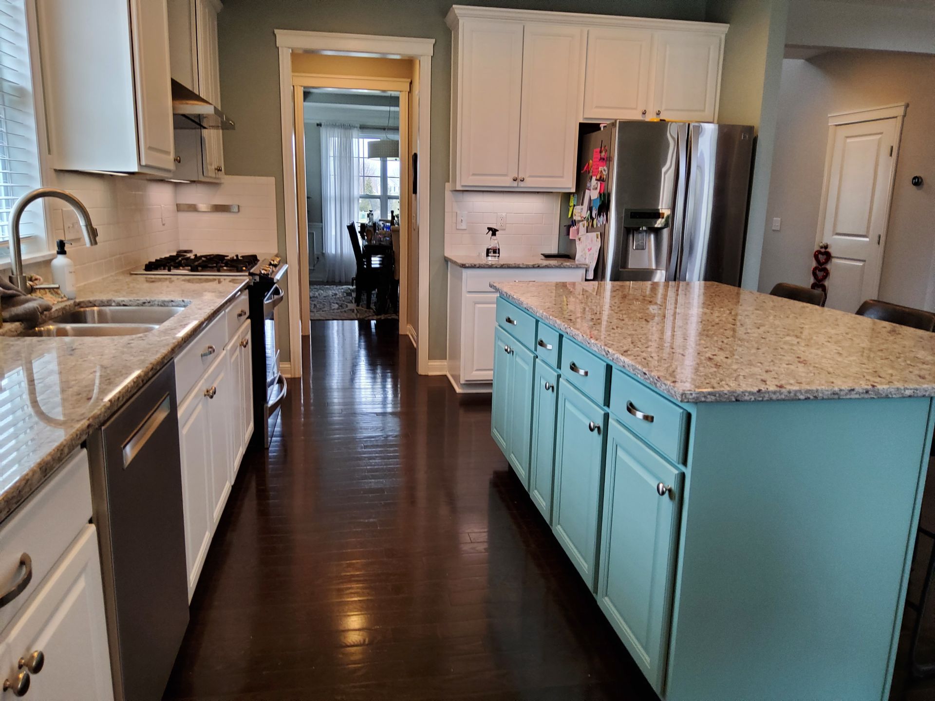A kitchen with white cabinets , granite counter tops , stainless steel appliances and a large island.