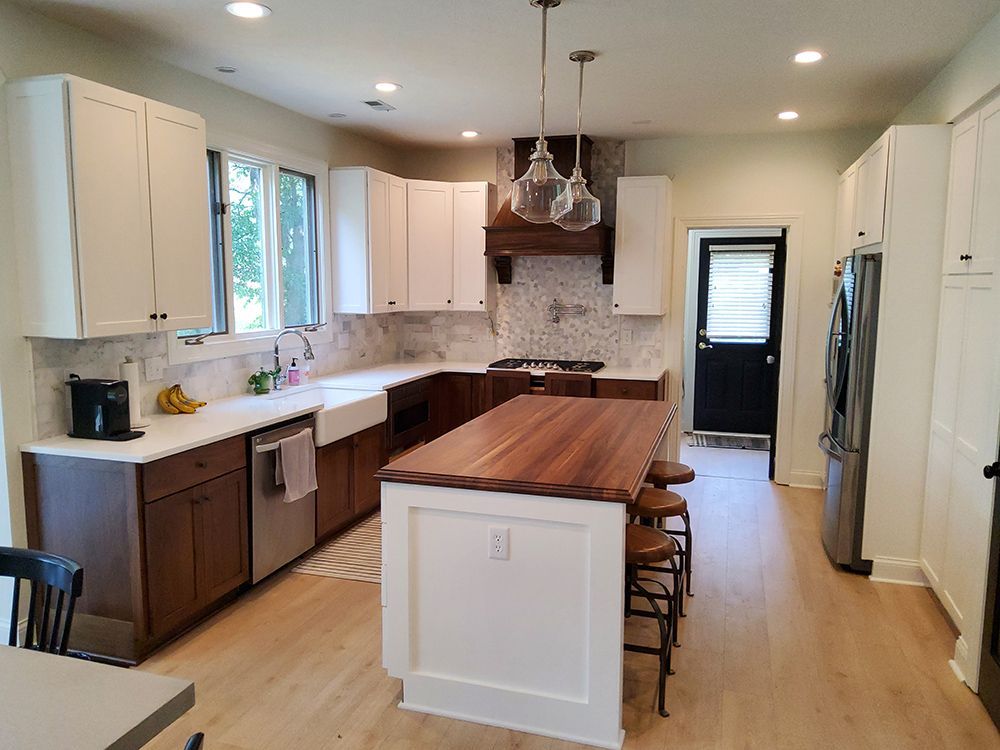 A kitchen with white cabinets and a large wooden island.