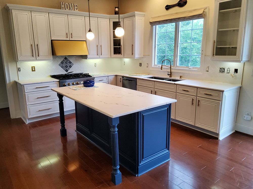 A kitchen with white cabinets and a large island in the middle.