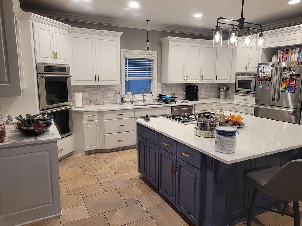 A kitchen with white cabinets and a blue island.