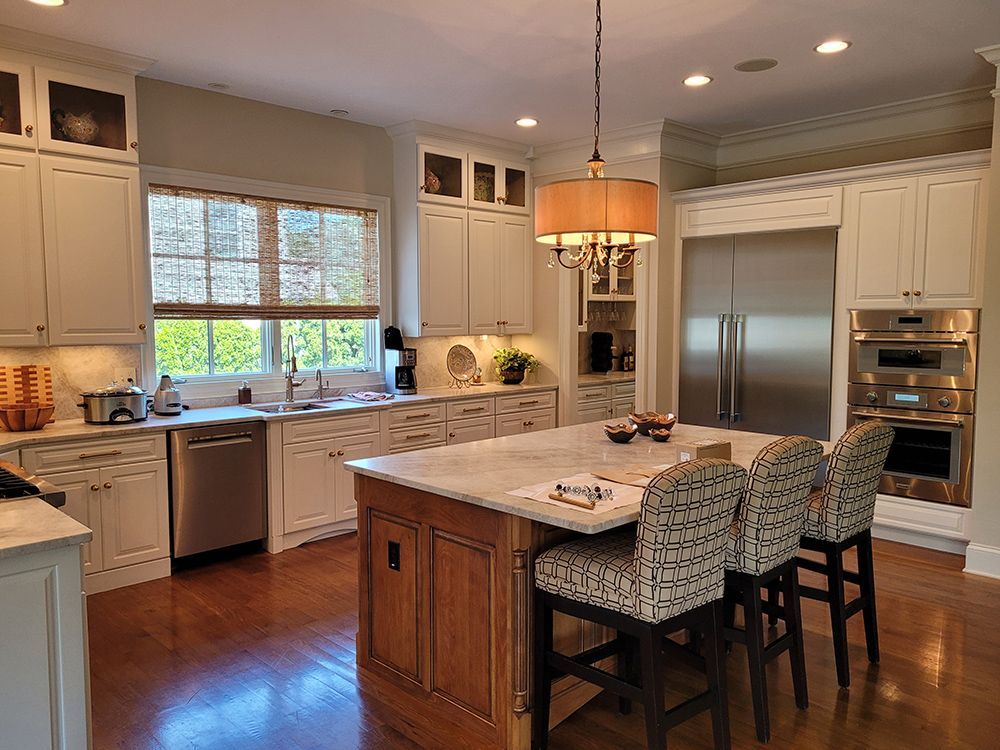A kitchen with white cabinets and stainless steel appliances and a large island.