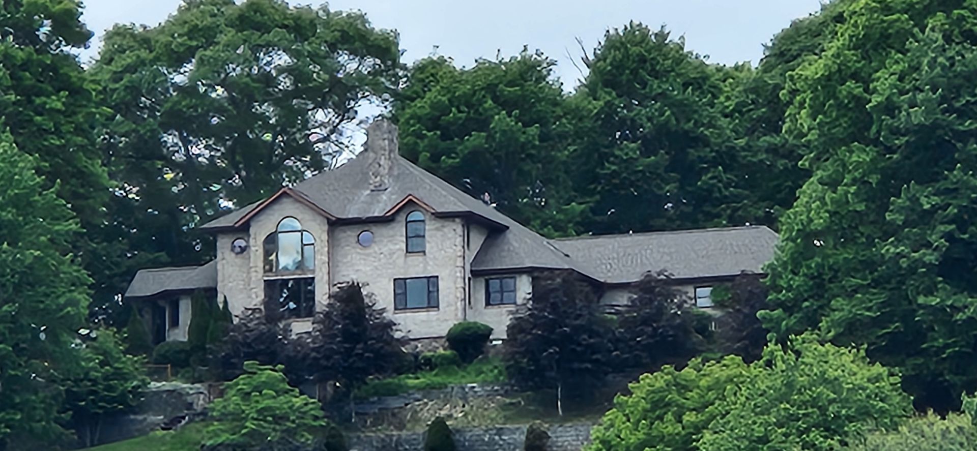 A large house is surrounded by trees on a hillside