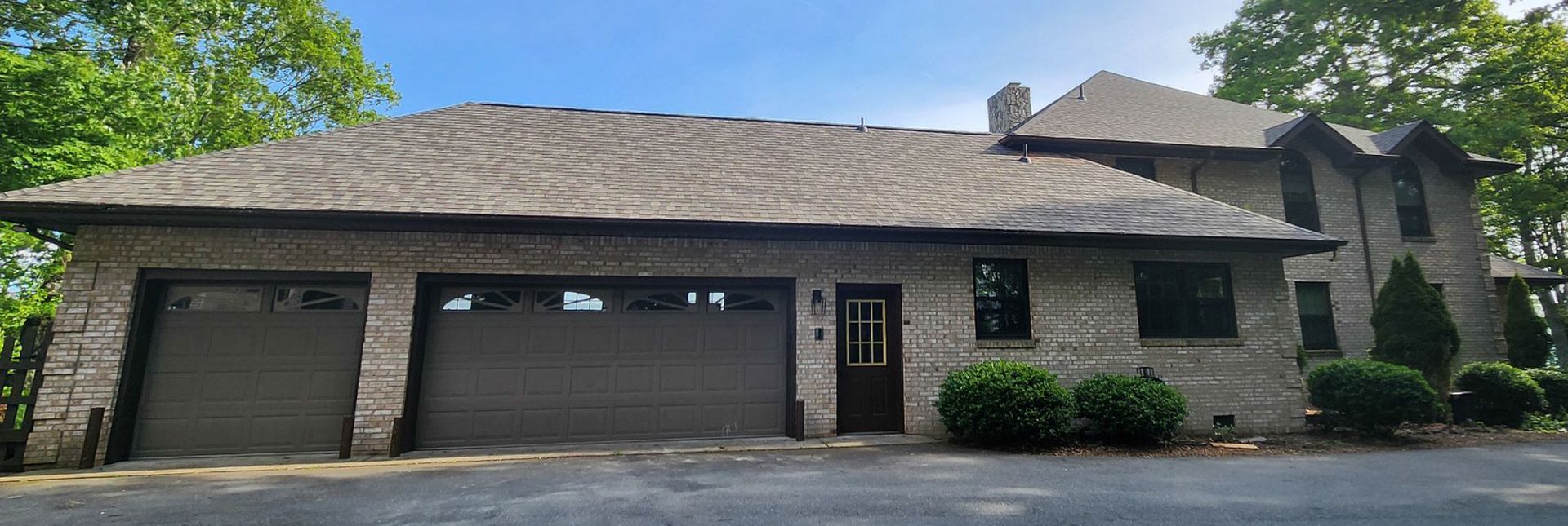 A large brick house with three garage doors and a roof.