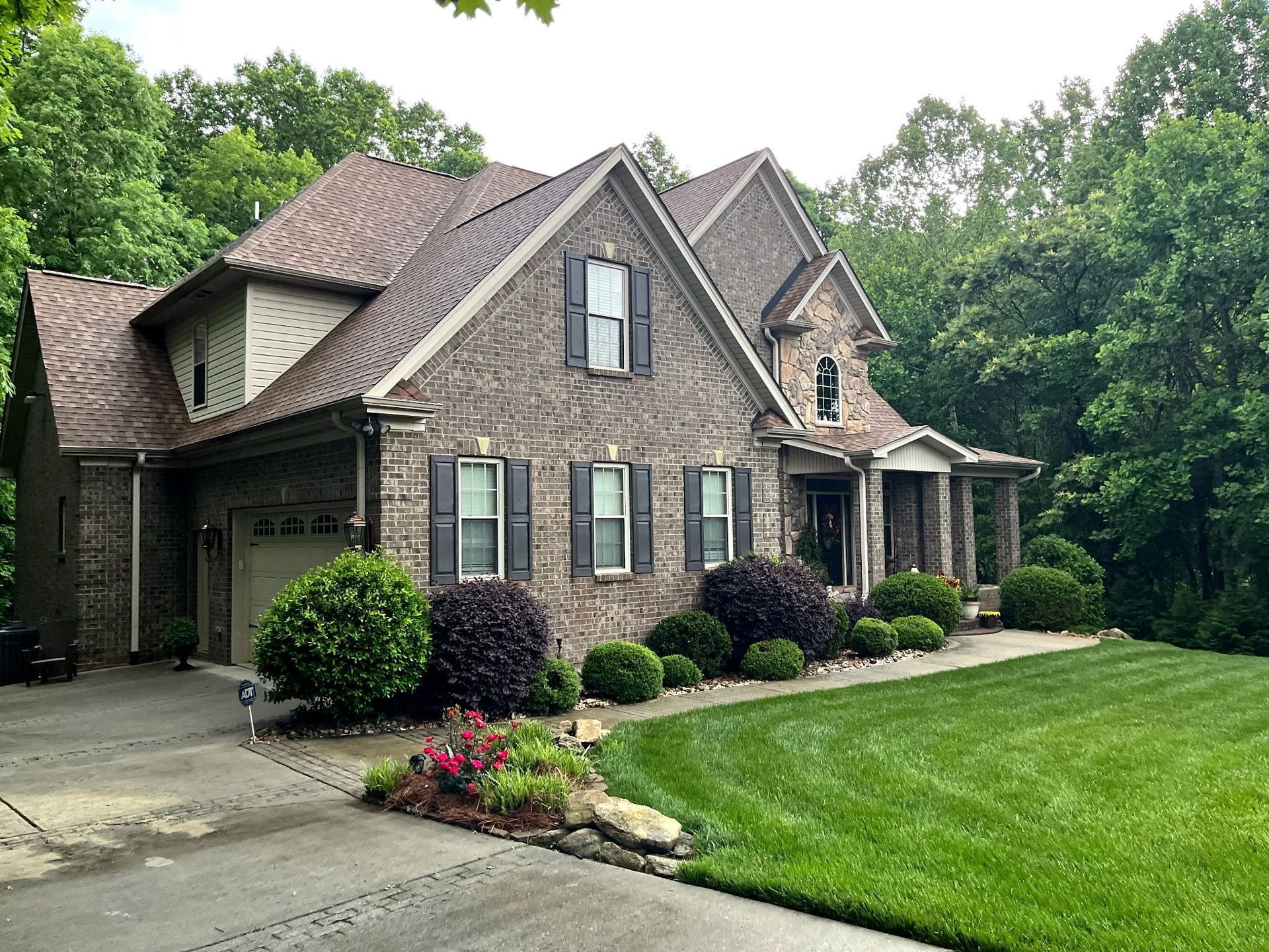 A large brick house with a lush green lawn in front of it.