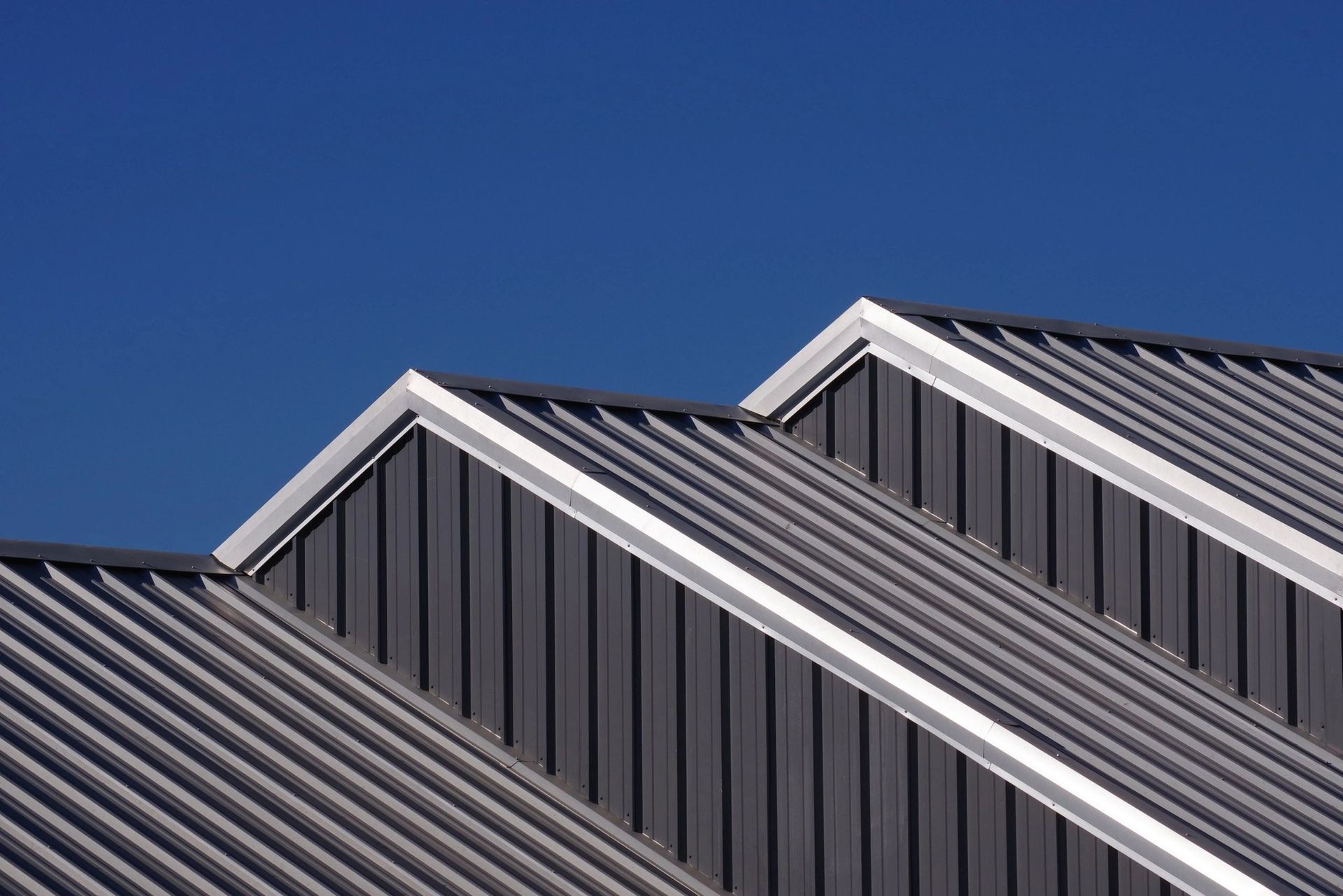A close up of a metal roof with a blue sky in the background.