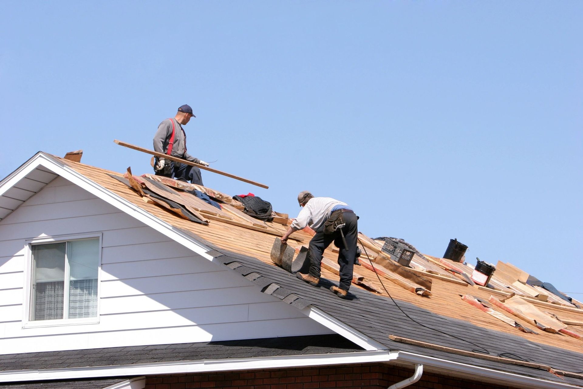 Two men are working on the roof of a house.