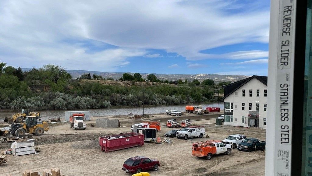 A construction site with a lot of trucks and tractors and a river in the background