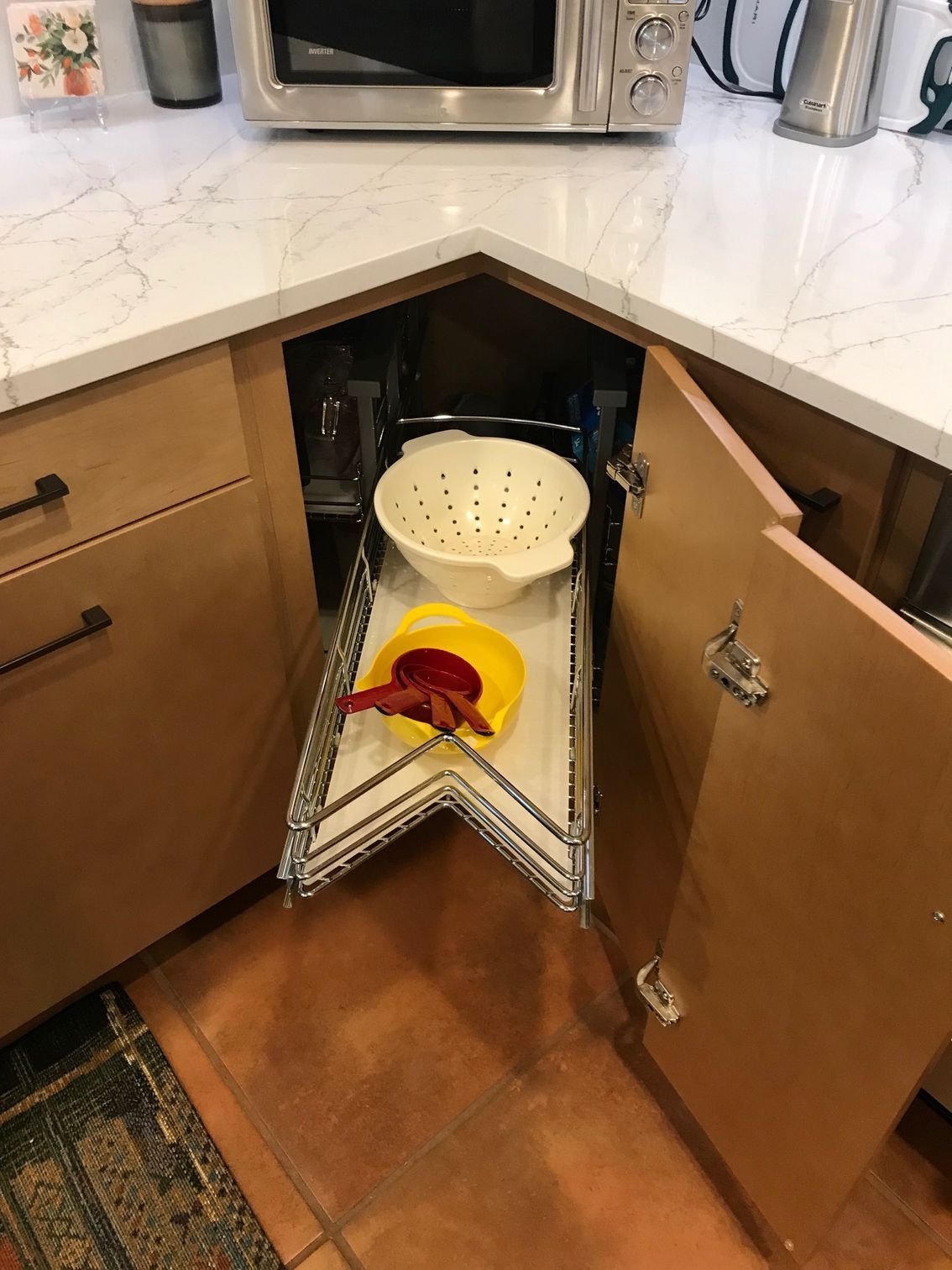 A kitchen with a microwave and a strainer in the corner.