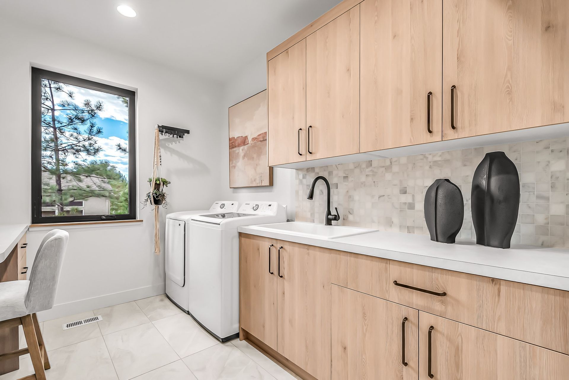 A laundry room with wooden cabinets, a washer and dryer, a sink, and a window