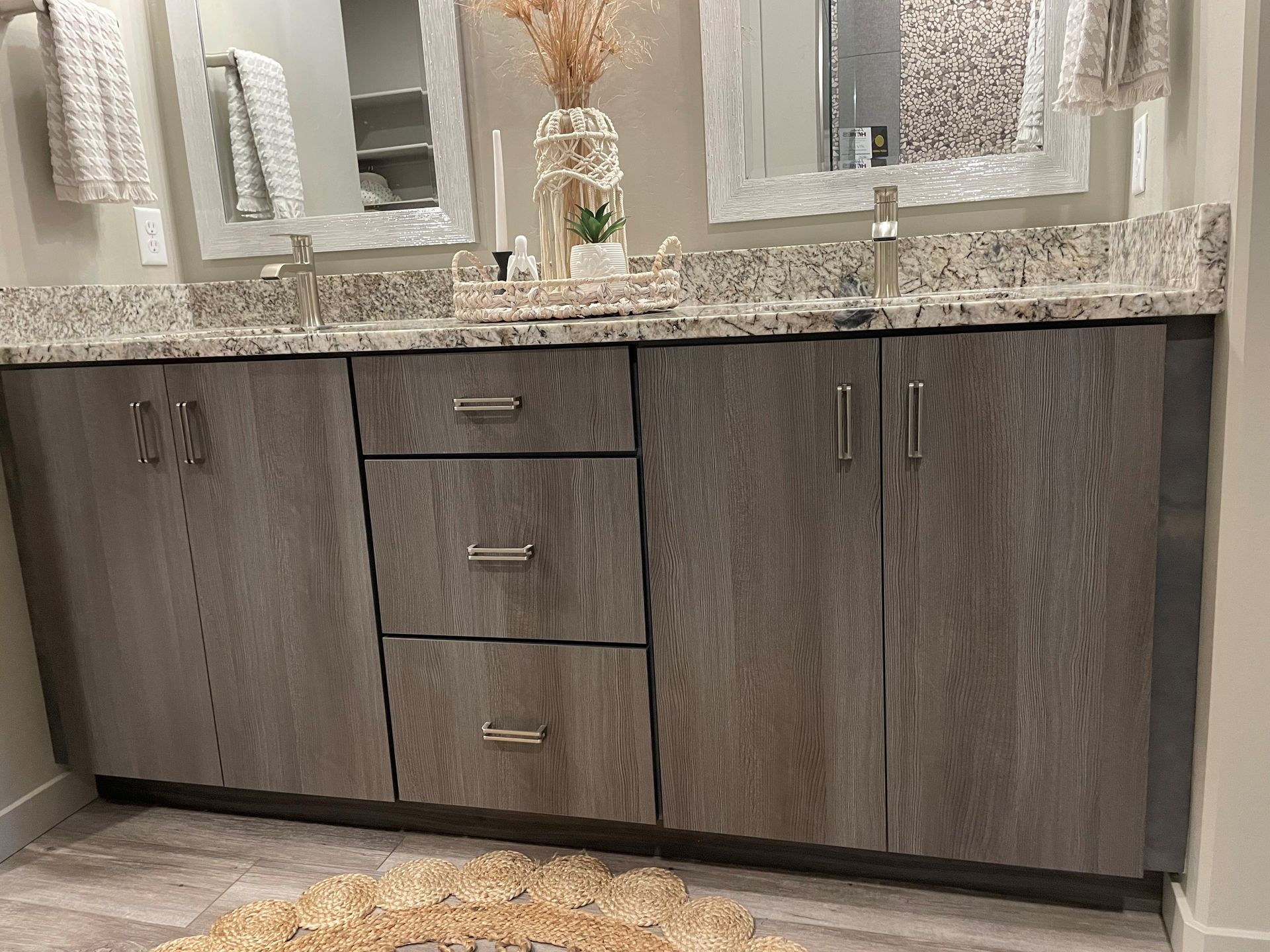 a bathroom with two sinks , two mirrors , and a rug .