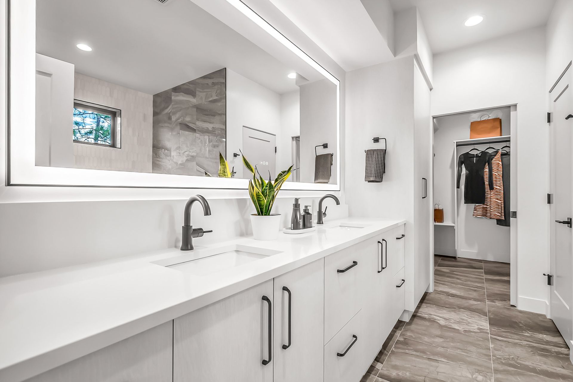 a bathroom with two sinks , a large mirror and a walk in closet .