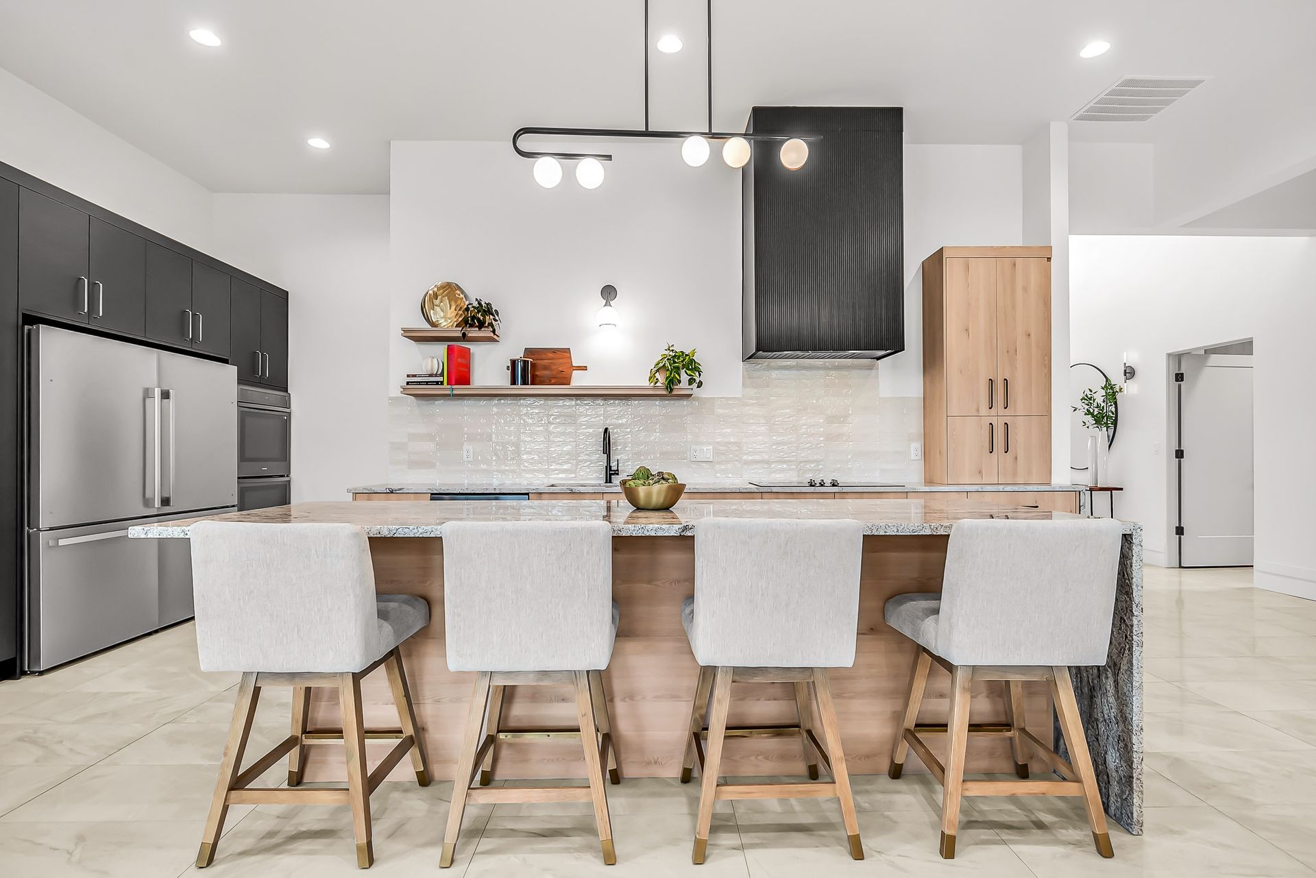 a kitchen with a large island , stools and a refrigerator .