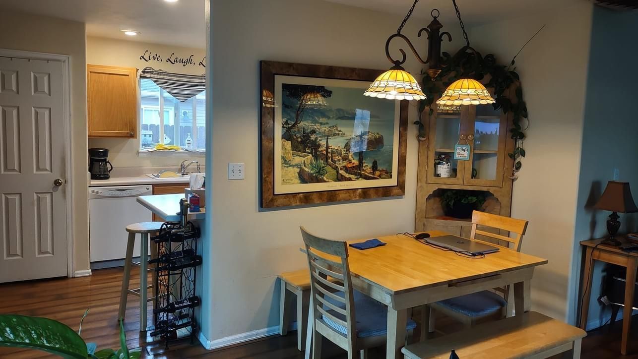 A dining room with a table and chairs and a painting on the wall