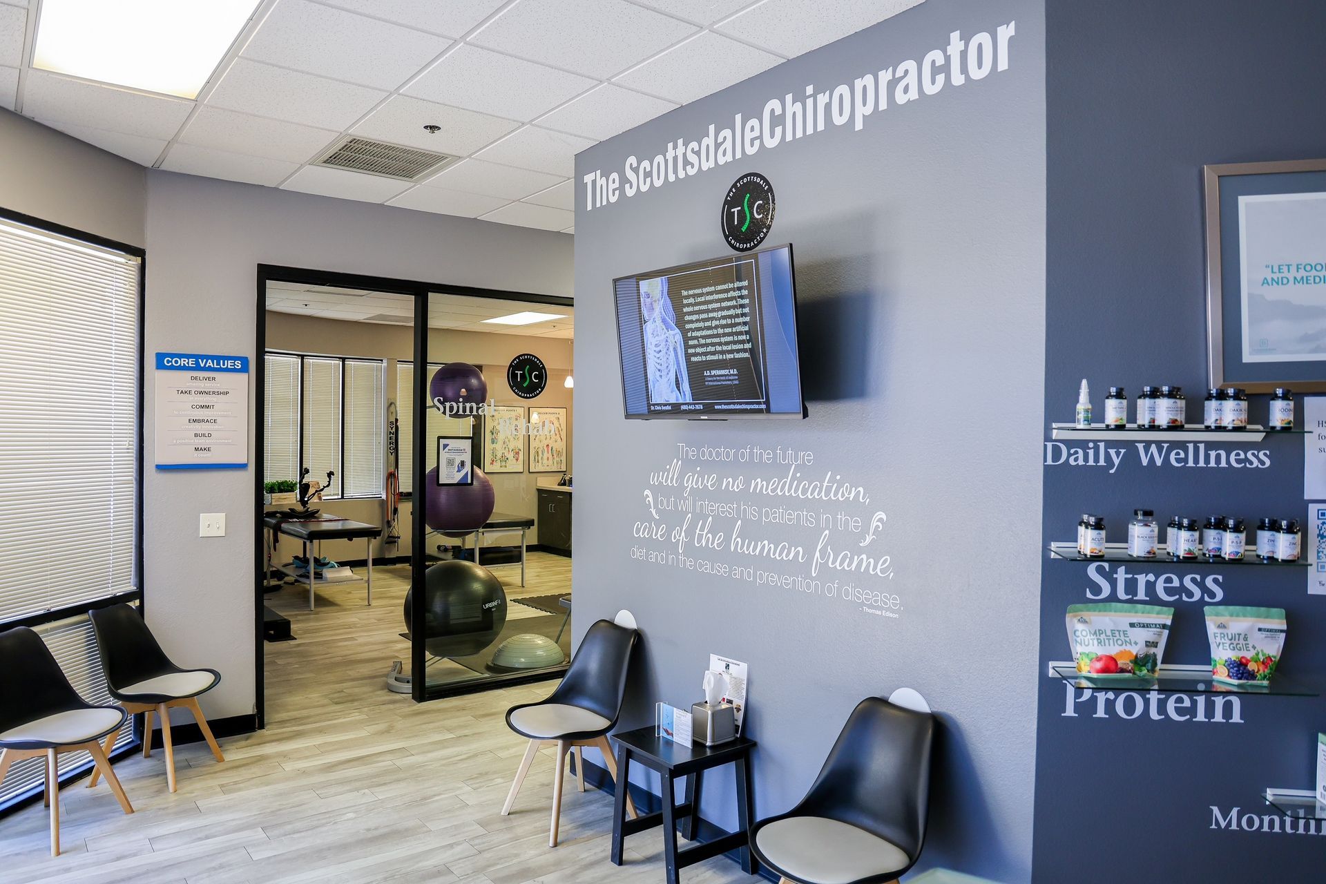 Reception area of The Scottsdale Chiropractor with a grey feature wall, seating, and a product display shelf.