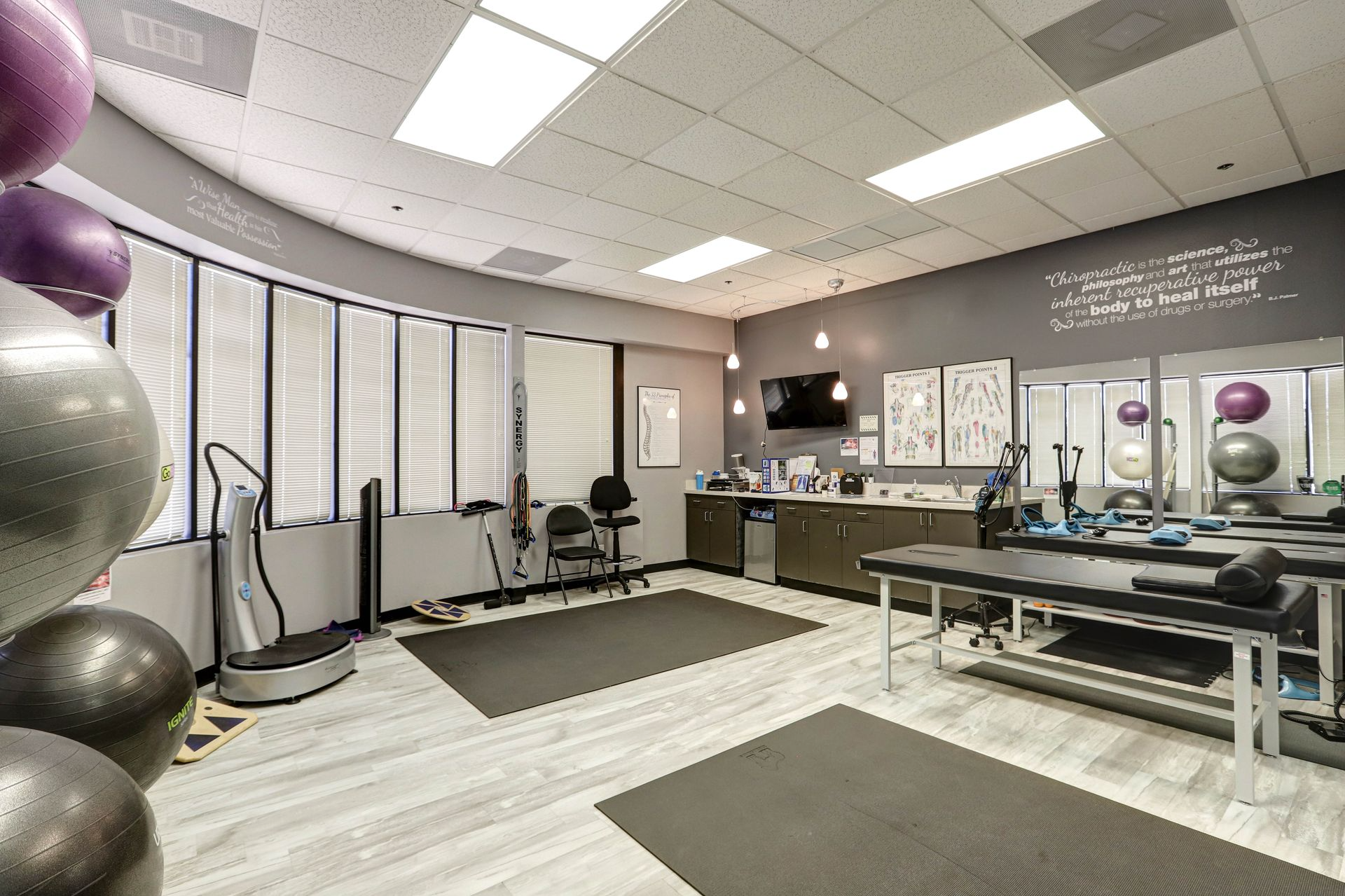 Physical therapy room, with exercise equipment, gray walls, and bright lighting.