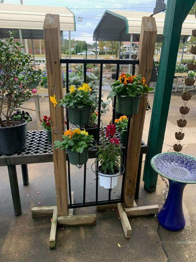 A wooden fence with flowers in pots hanging from it.