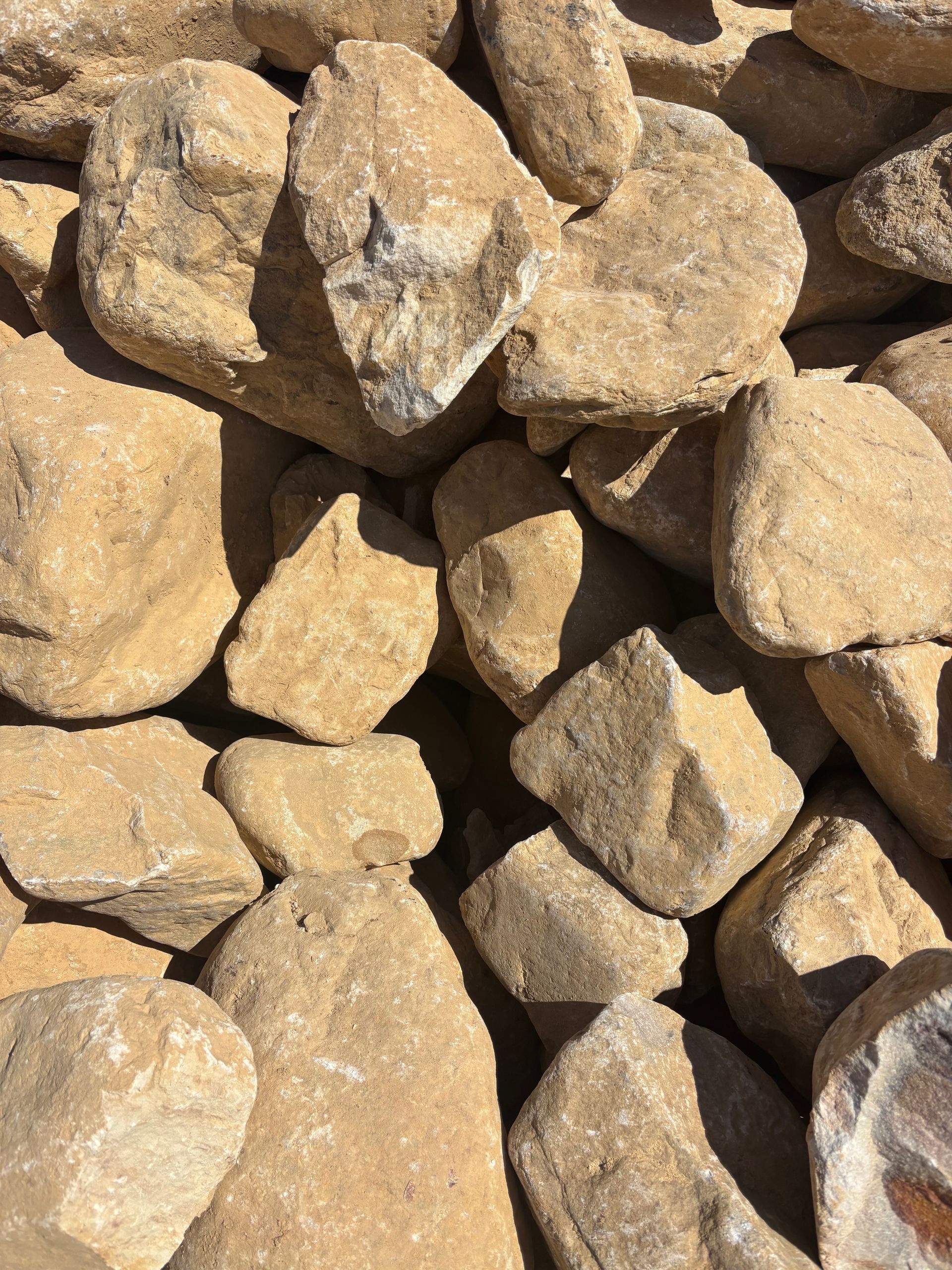 Pile of tan, irregular rocks stacked closely together in sunlight