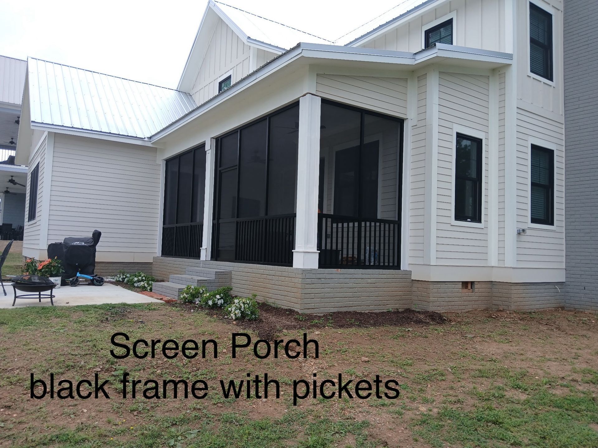 White house with a screened porch and black railings on a grassy yard