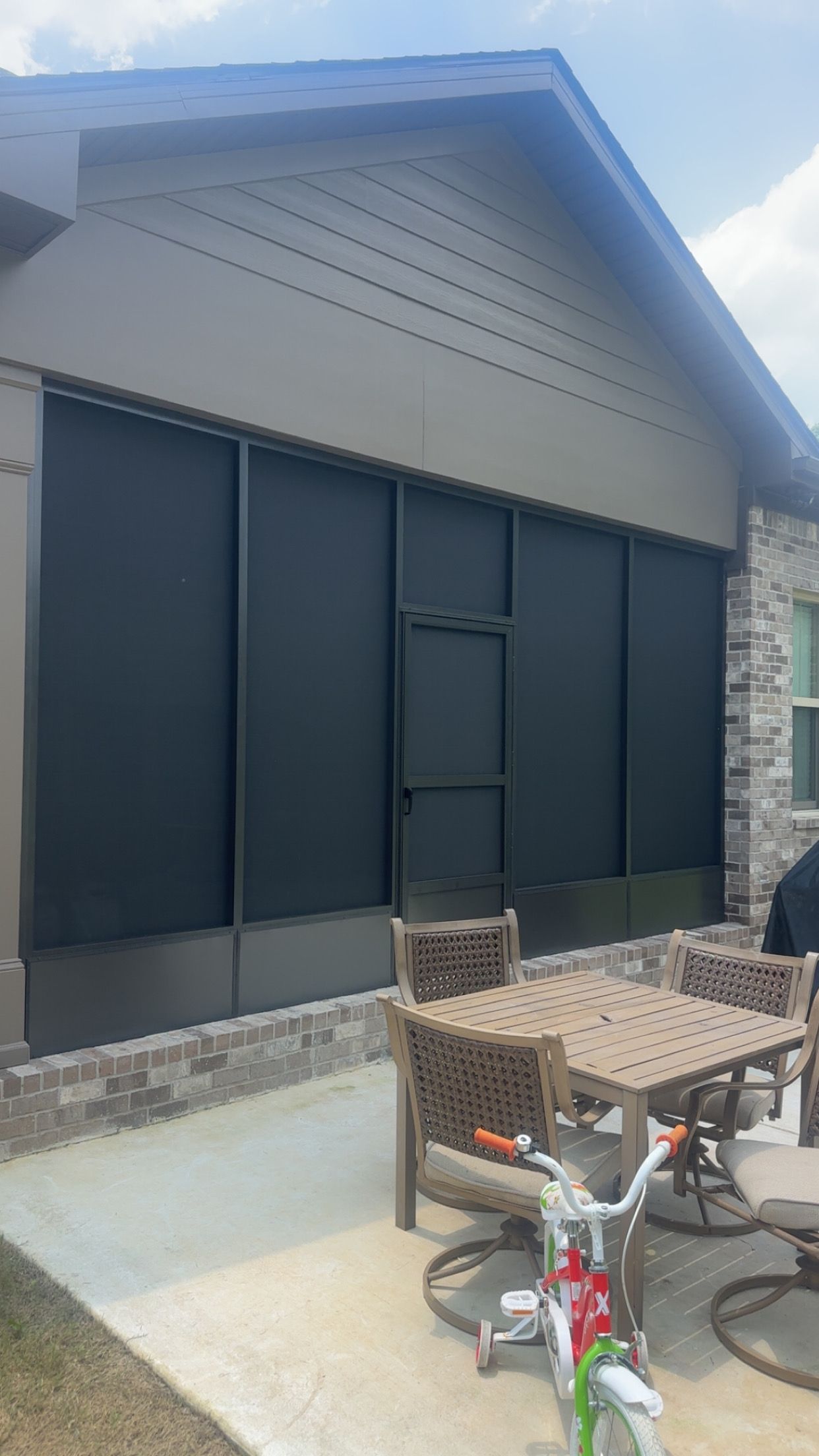 House exterior with dark window shutters and a bicycle parked on a patio in front