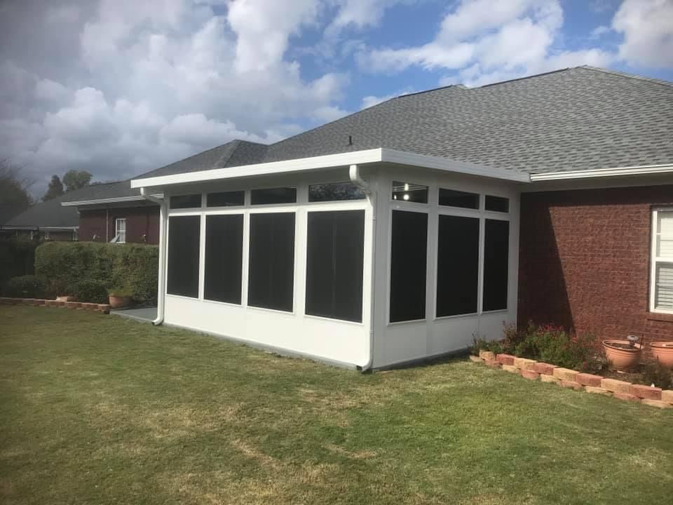 Screened sunroom attached to a brick house with white trim and a shingled roof