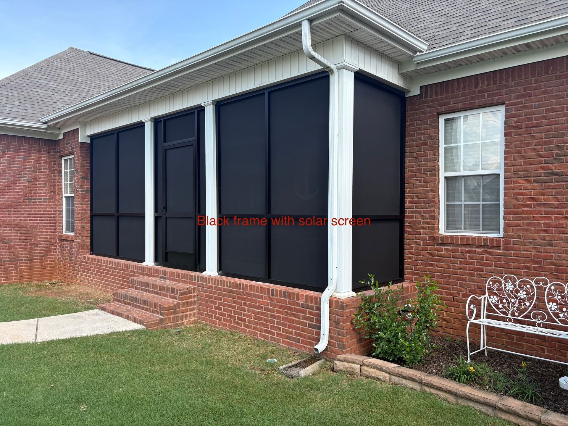 Brick house with black screened porch, white trim, and a small front lawn