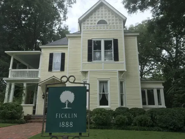 Historic pale yellow house with a green sign reading “Ficklin 1888” in front