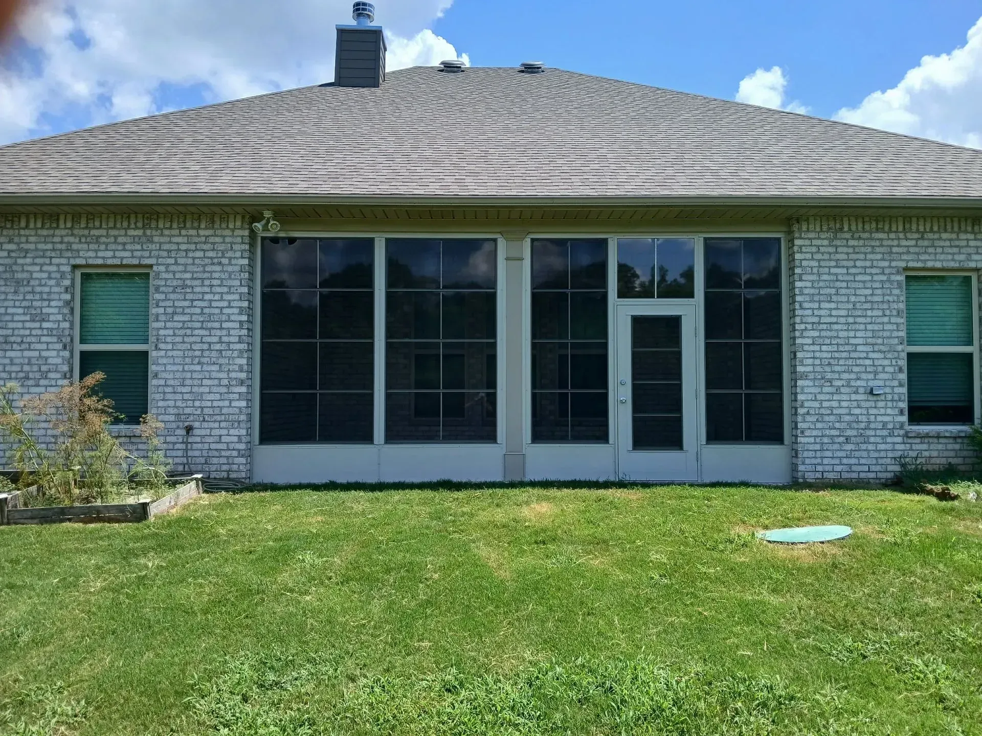 Back view of a single-story house with white siding, large windows, and a grassy yard
