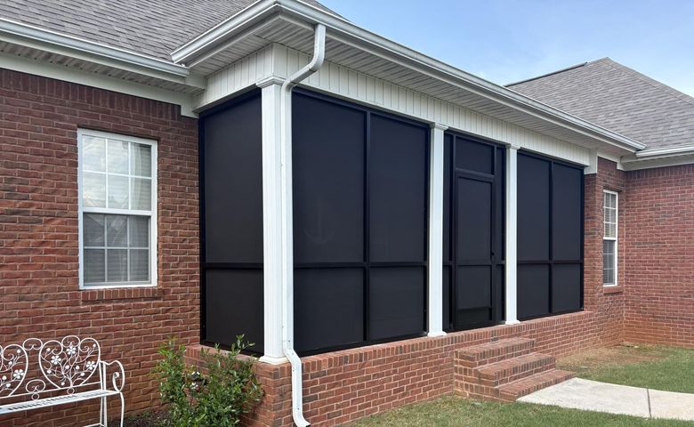 Brick house exterior with large black window covers and white trim under a gray roof