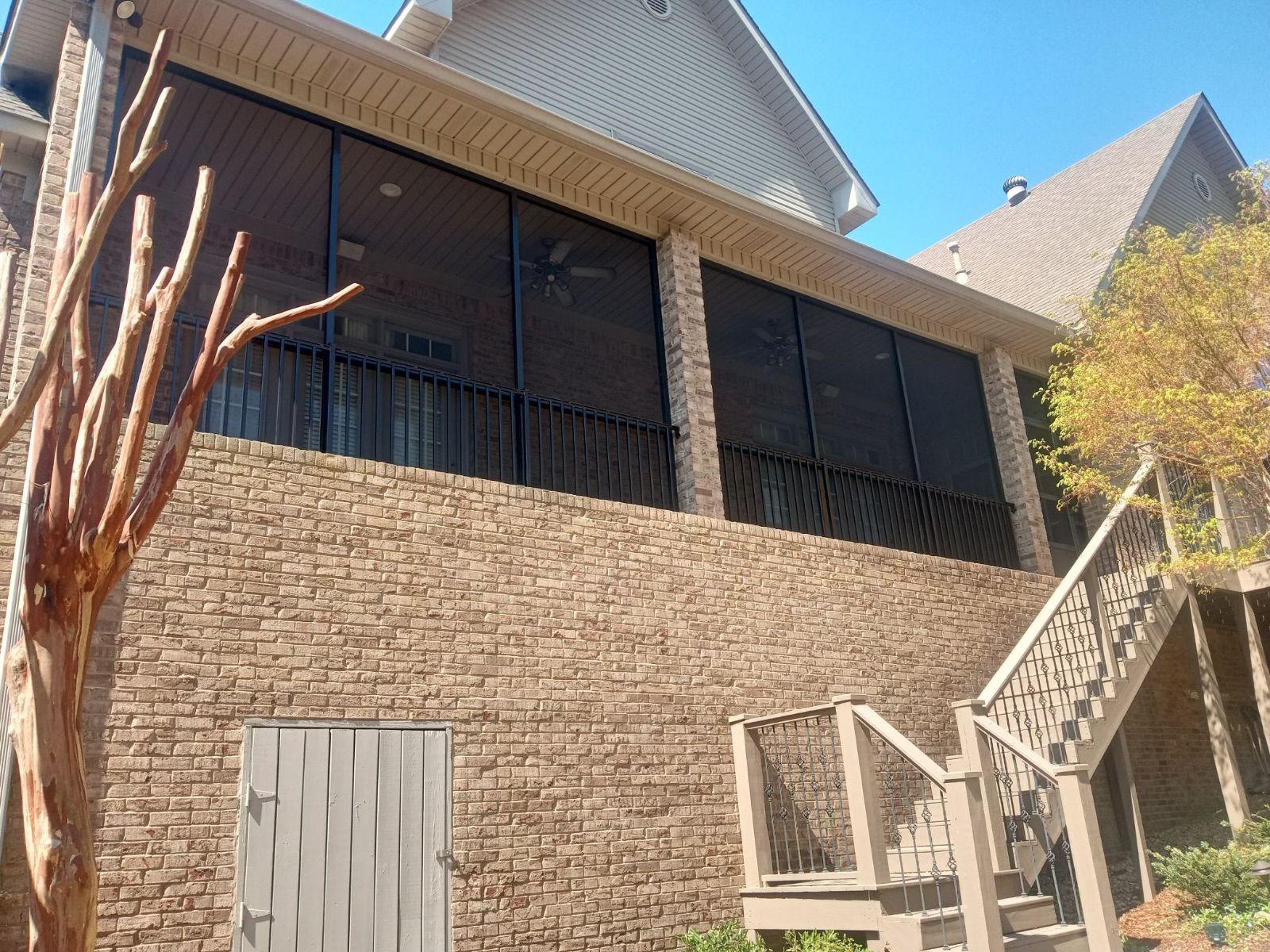 Brick house exterior with balcony, stairs, and a sloped roof in sunlight