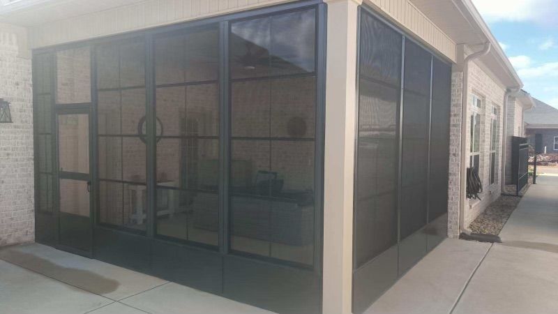 Black mesh patio enclosure on a sidewalk beside a beige building.