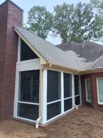 Screened porch addition with white trim, gray roof, brick chimney, and large windows on a house