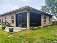 Single-story stone house with screened patio and green lawn