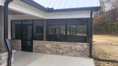 Exterior of a modern stone-and-glass building with a covered porch and concrete walkway
