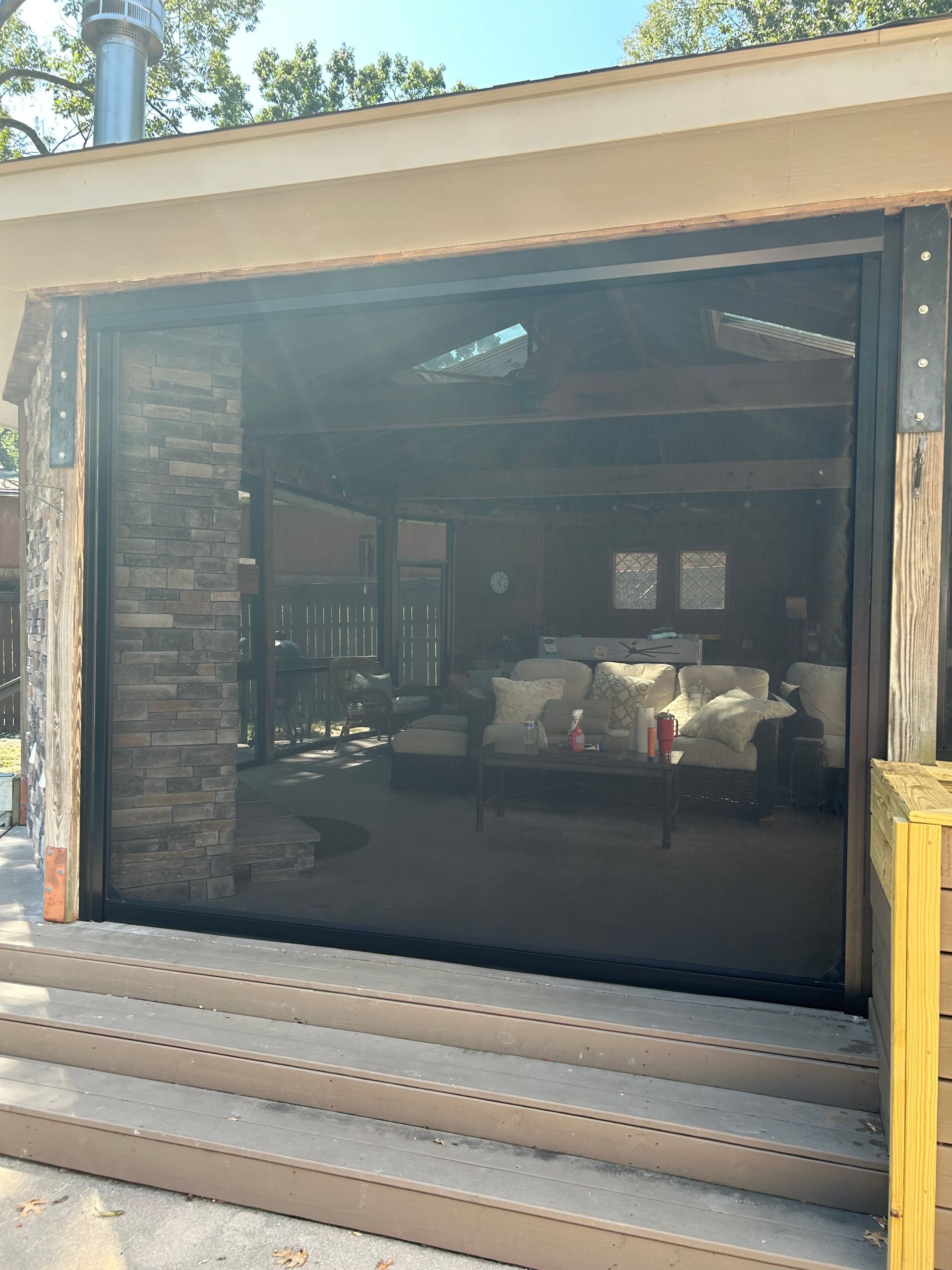 Covered outdoor patio with screened opening, stone columns, and seating visible inside