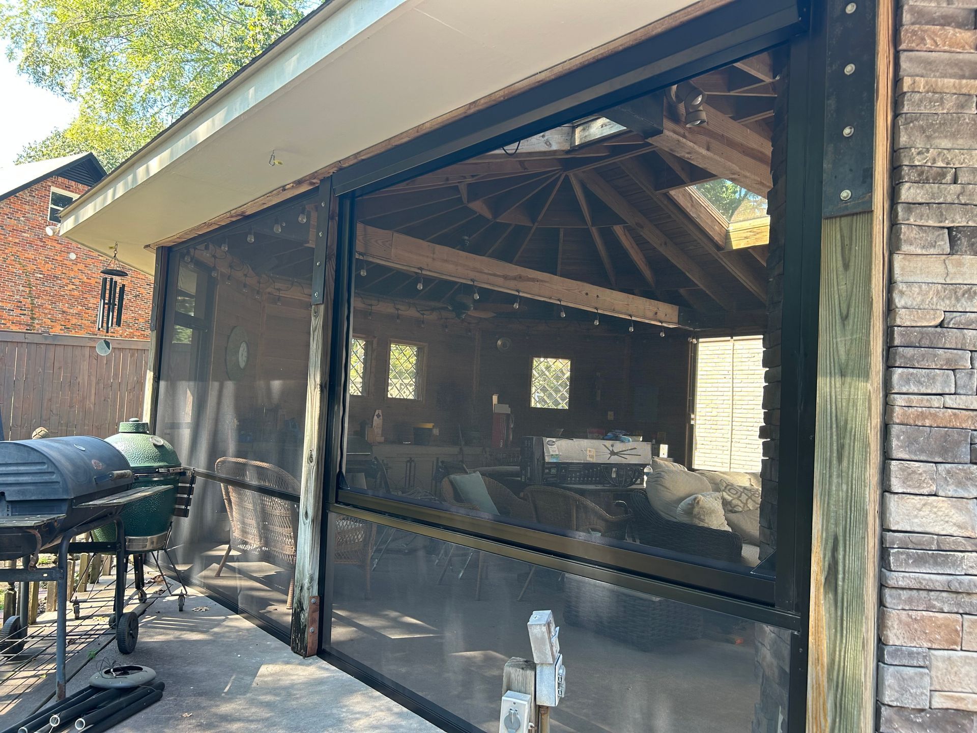 Screened patio with barbecue grill, glass doors, and stone siding on a house