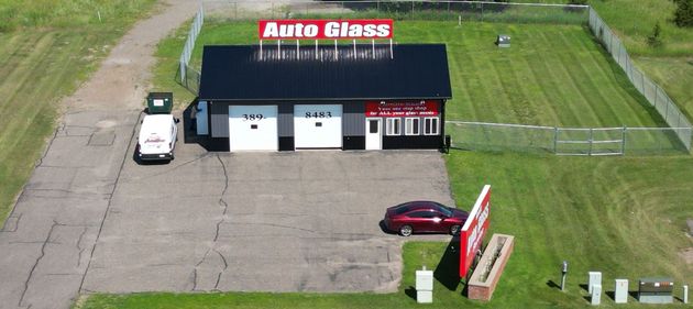 Aerial view of Arta Glass building with parked cars and grassy surroundings