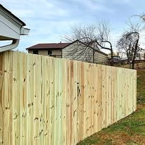 Wooden fence in front of a house, under a cloudy sky.