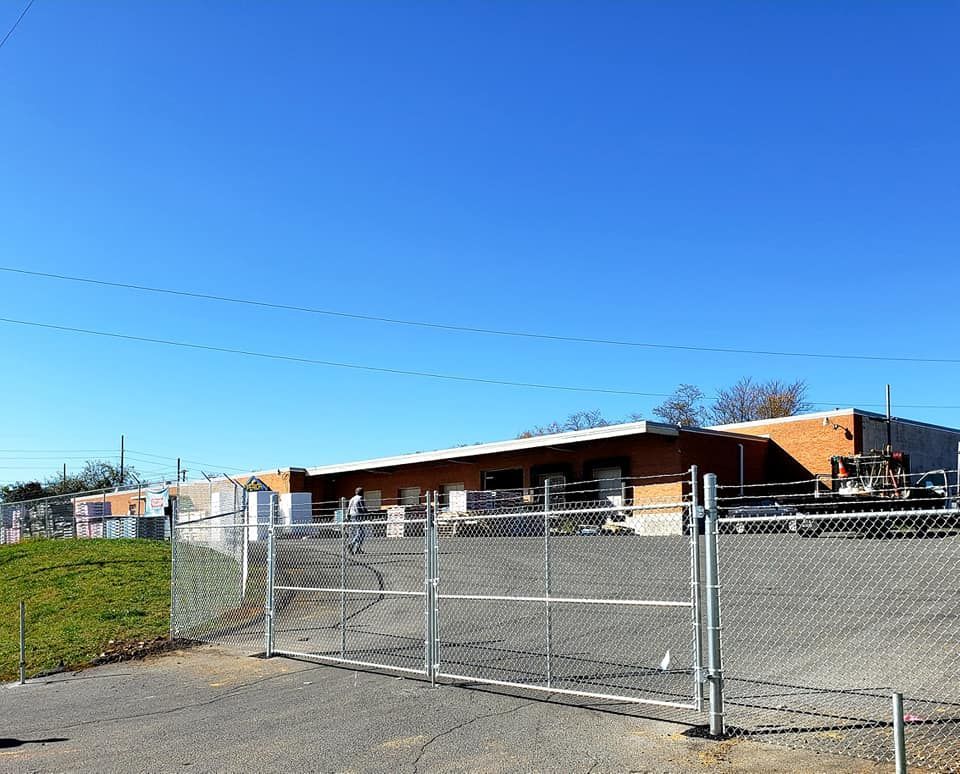 Exterior view of a commercial building behind a chain-link fence on a clear day.