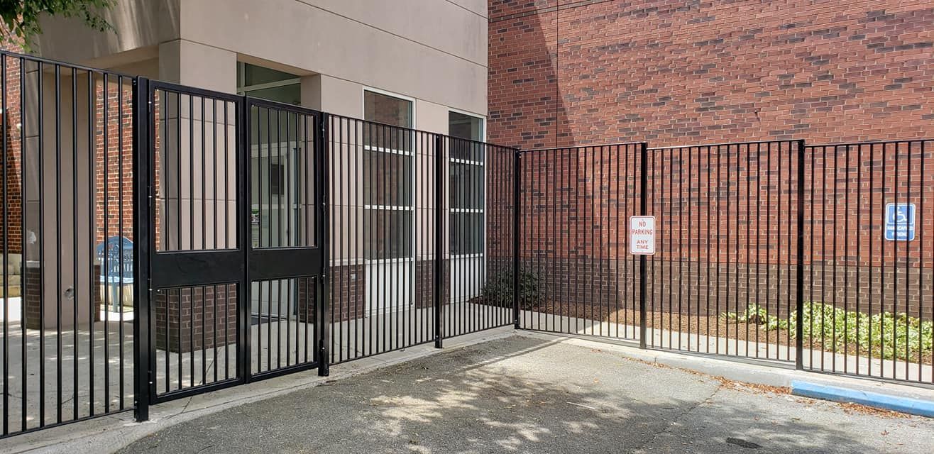 Black metal fence around a building with brick walls.