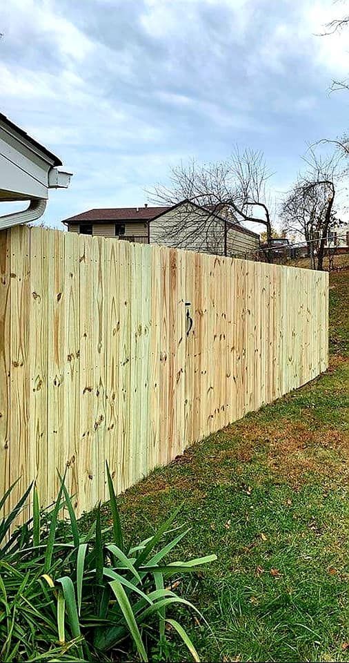 A new wooden fence bordering a grassy yard under a cloudy sky.