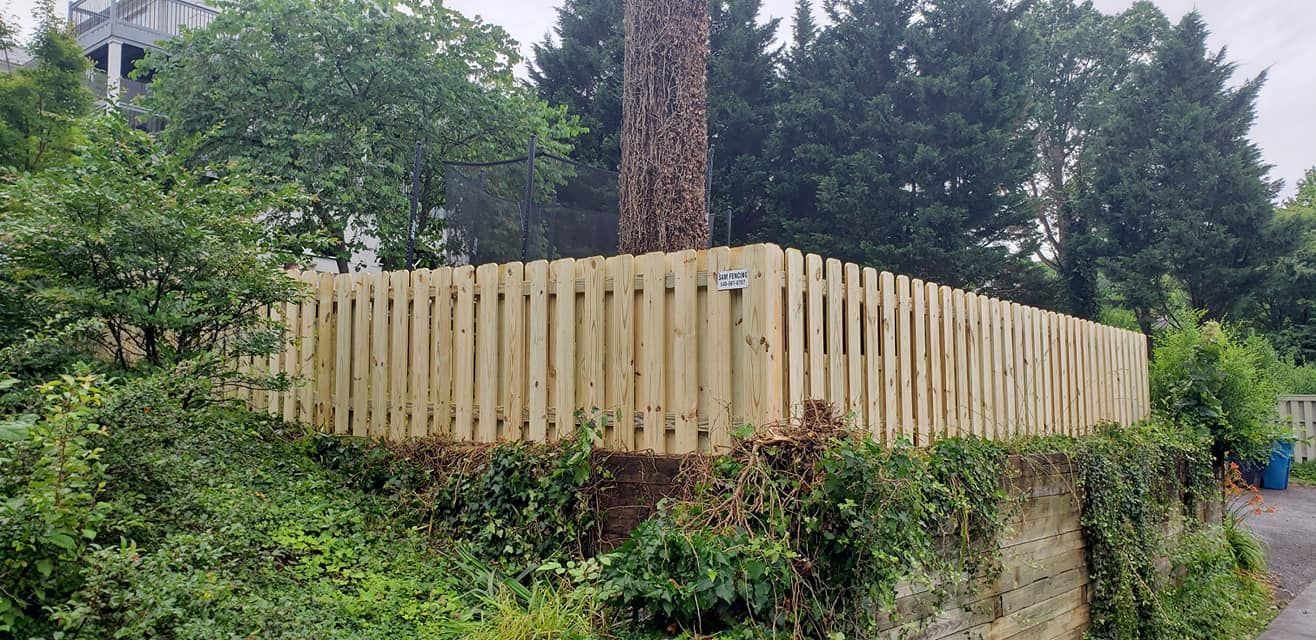 Wooden fence encloses a tree on a hillside covered in vegetation.