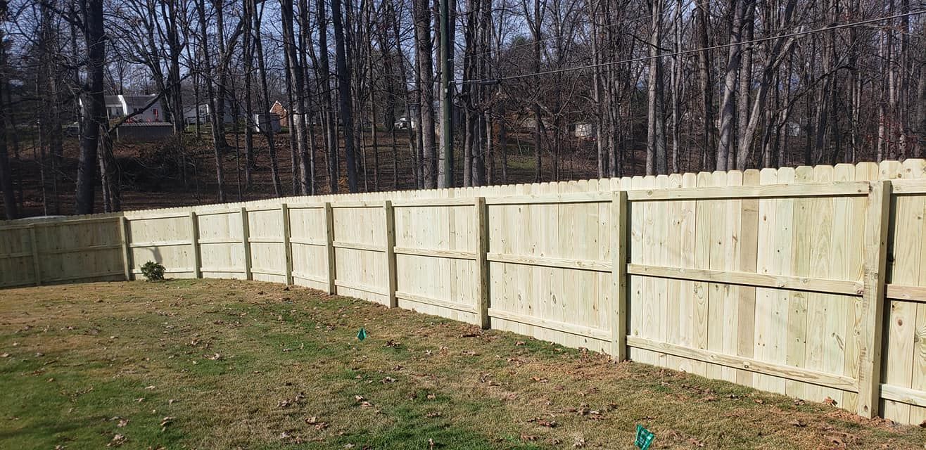 Wooden fence in a yard with trees in the background.