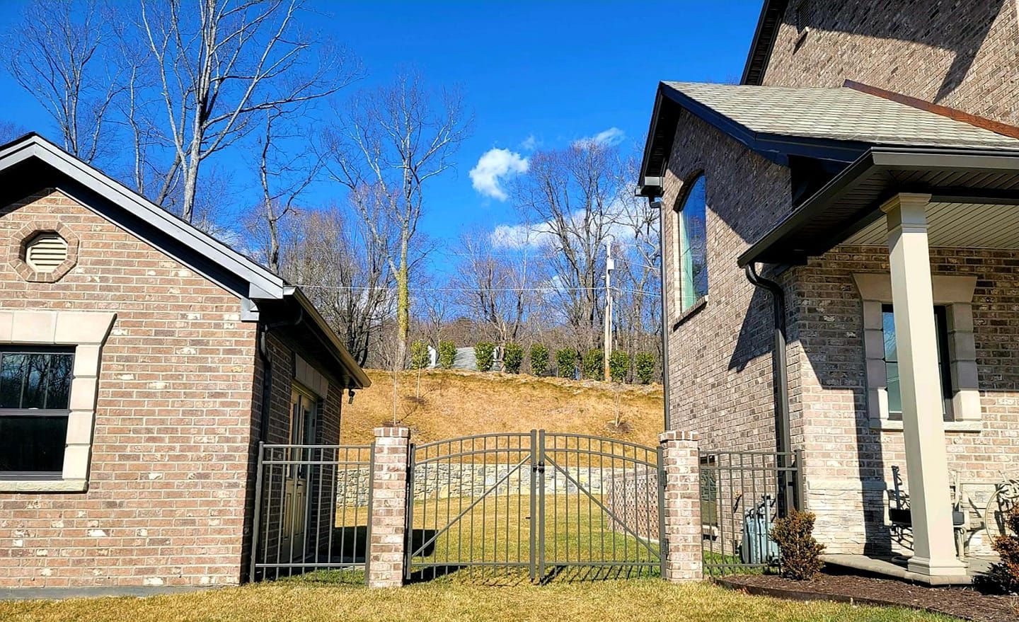 Brick buildings with a wrought iron fence, sunny day, blue sky, and bare trees.