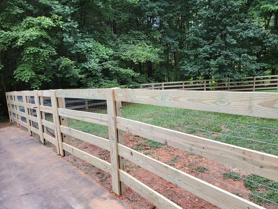 Wooden fence in a grassy area, with trees in the background.