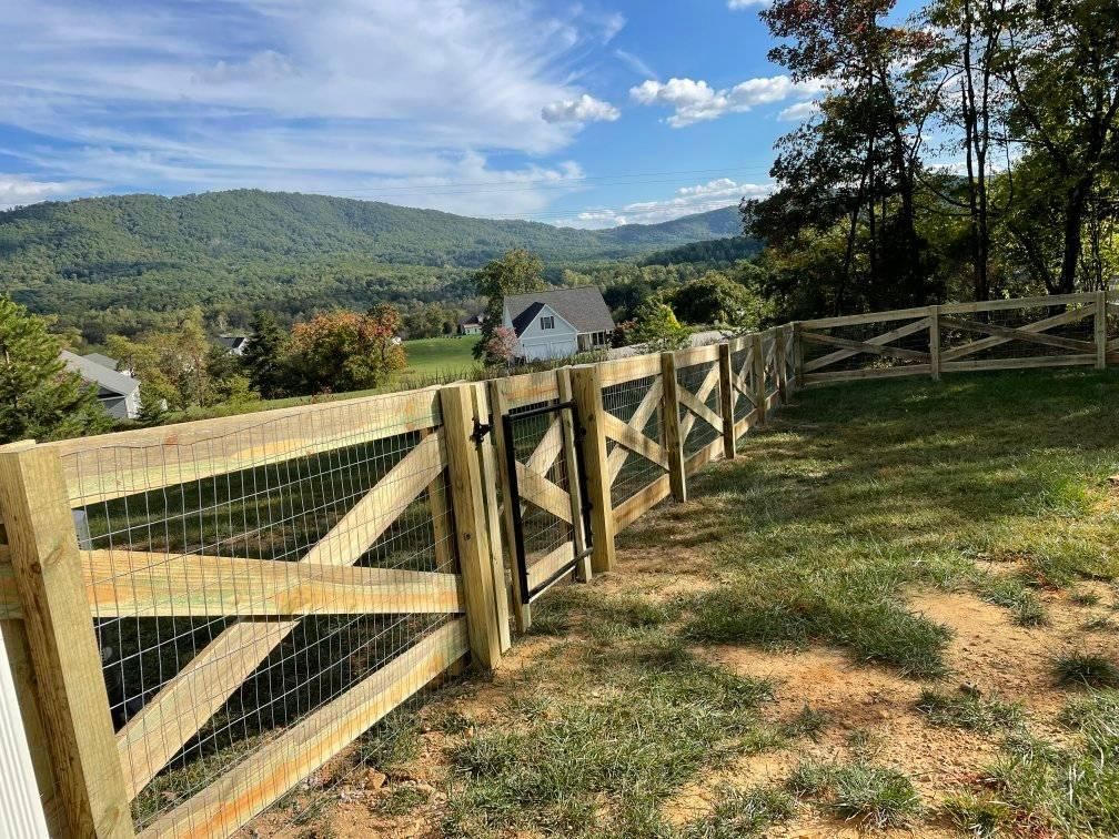 Wooden fence with gate, grassy yard, and mountain backdrop on a sunny day.