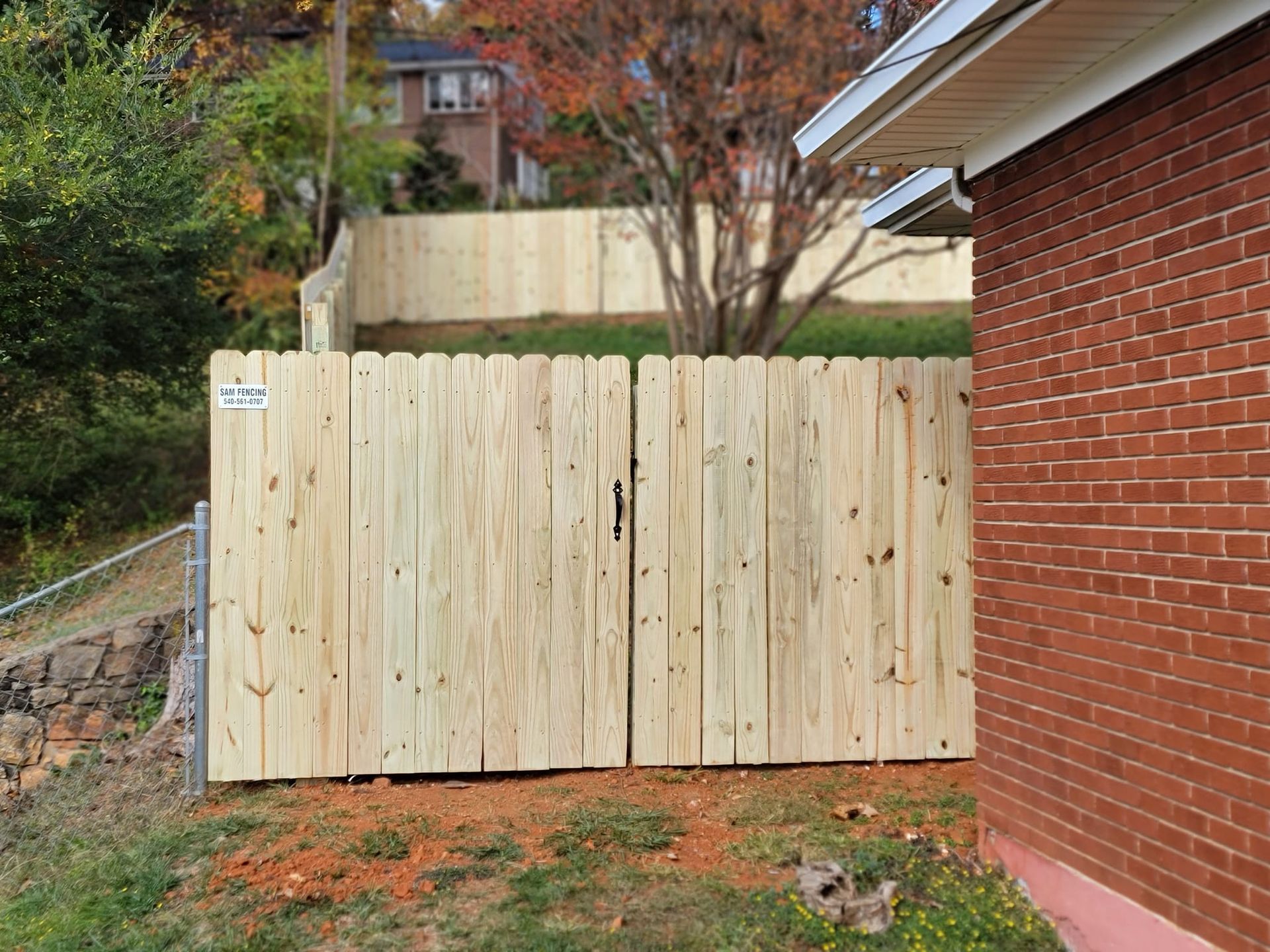 Wooden gate in backyard next to a brick building.