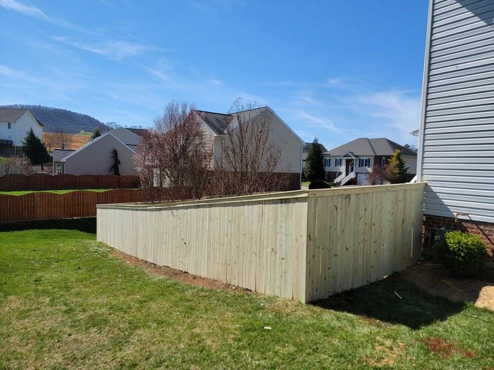 Wooden privacy fence in a backyard, beside a house, on a sunny day.