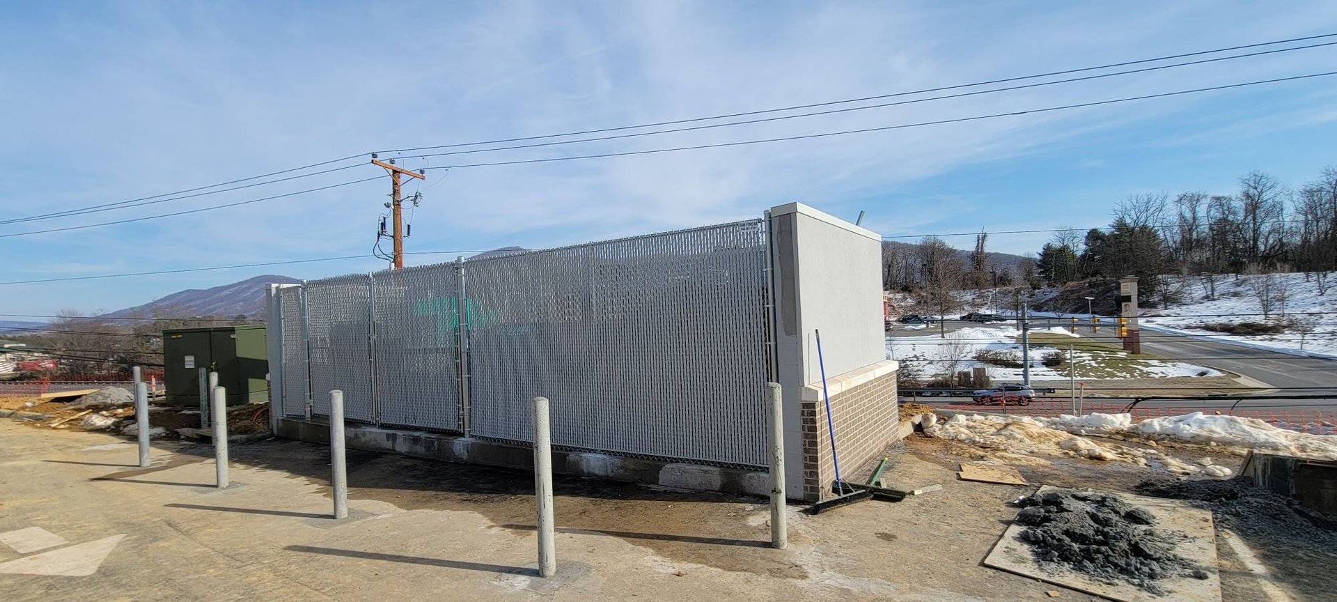 Construction site with a covered building, power lines, and snow on the ground.